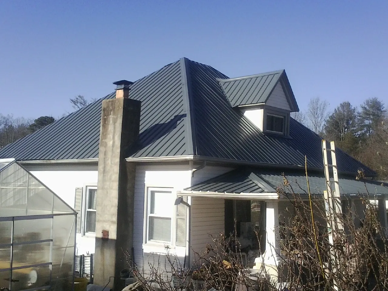 Dark blue standing seam metal roof on a white farmhouse with dormer — Slate & Tile Roof Repair by Roofing Brothers in Roann