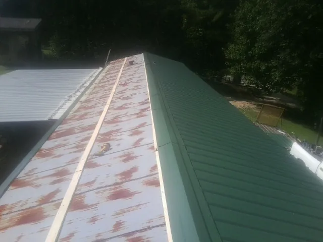 Old rusted panels beside newly installed green metal roofing — Wind Damage Roof Repair by Roofing Brothers in Roann