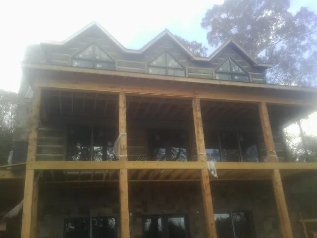 Dormers and porch framing on a large log home under construction — Roof Coating work by our crew in Roann