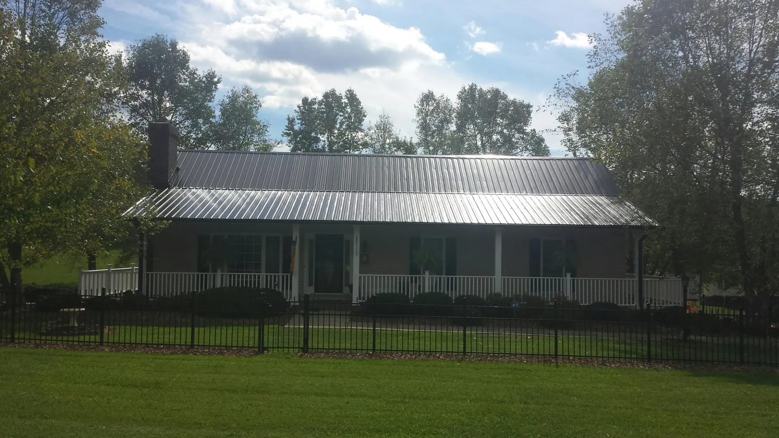 Gray metal roof on a brick ranch with a full width front porch — Gutter Guard Installation work by our crew in Roann