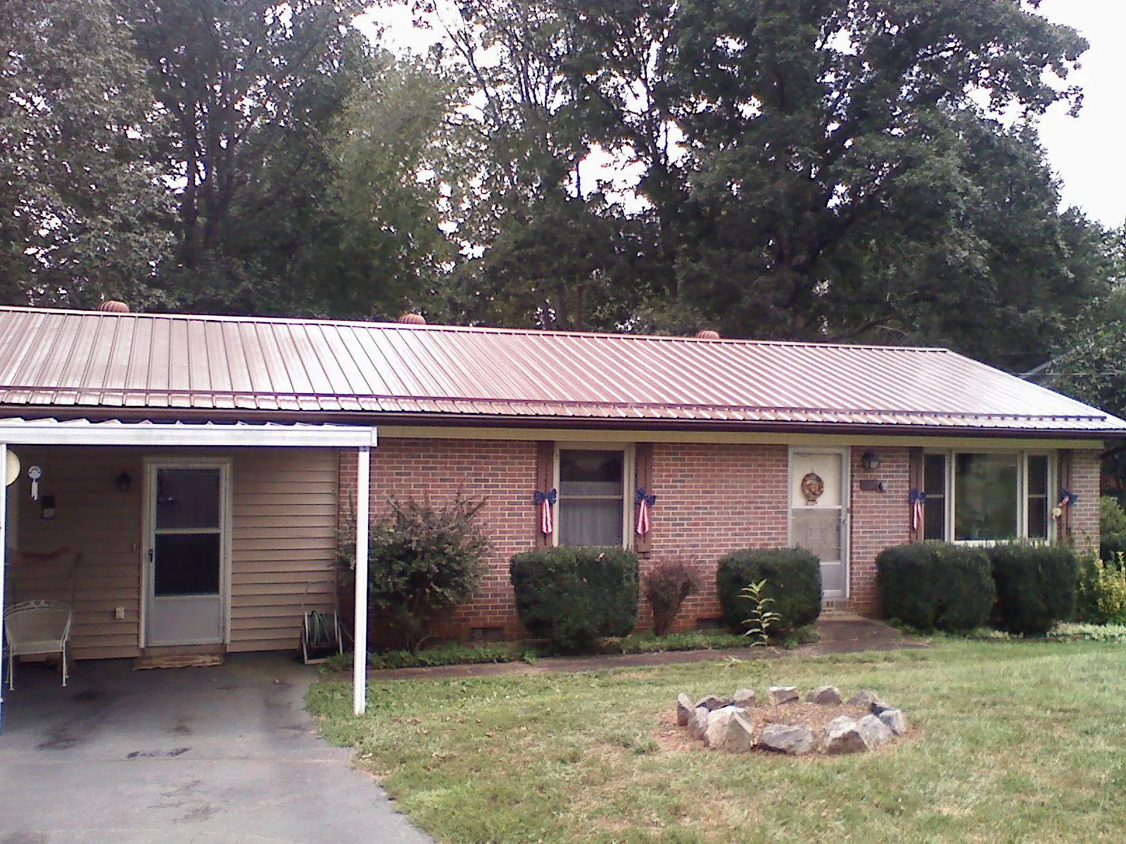 Bronze metal roof and carport on a brick ranch home — Roof Repair work by our crew in Roann