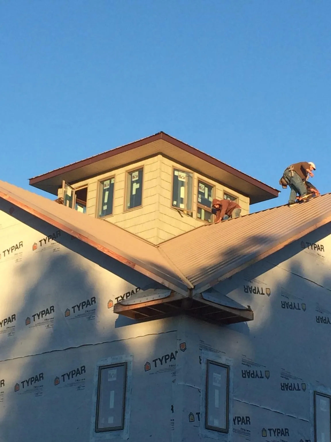 Roofers working around a rooftop cupola on a new metal roof at sunset — Roof Waterproofing in Roann by Roofing Brothers